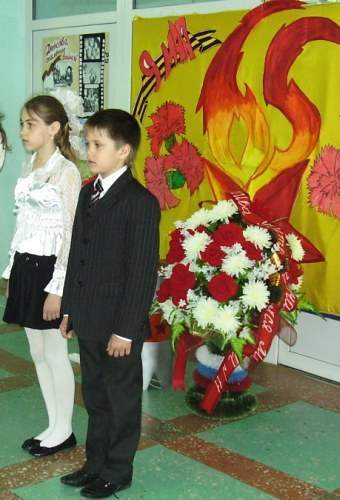 Лысенко Анна, Петерс Ростислав несут почетный караул на посту №1 у импровизированного Вечного огня в фойе школы.